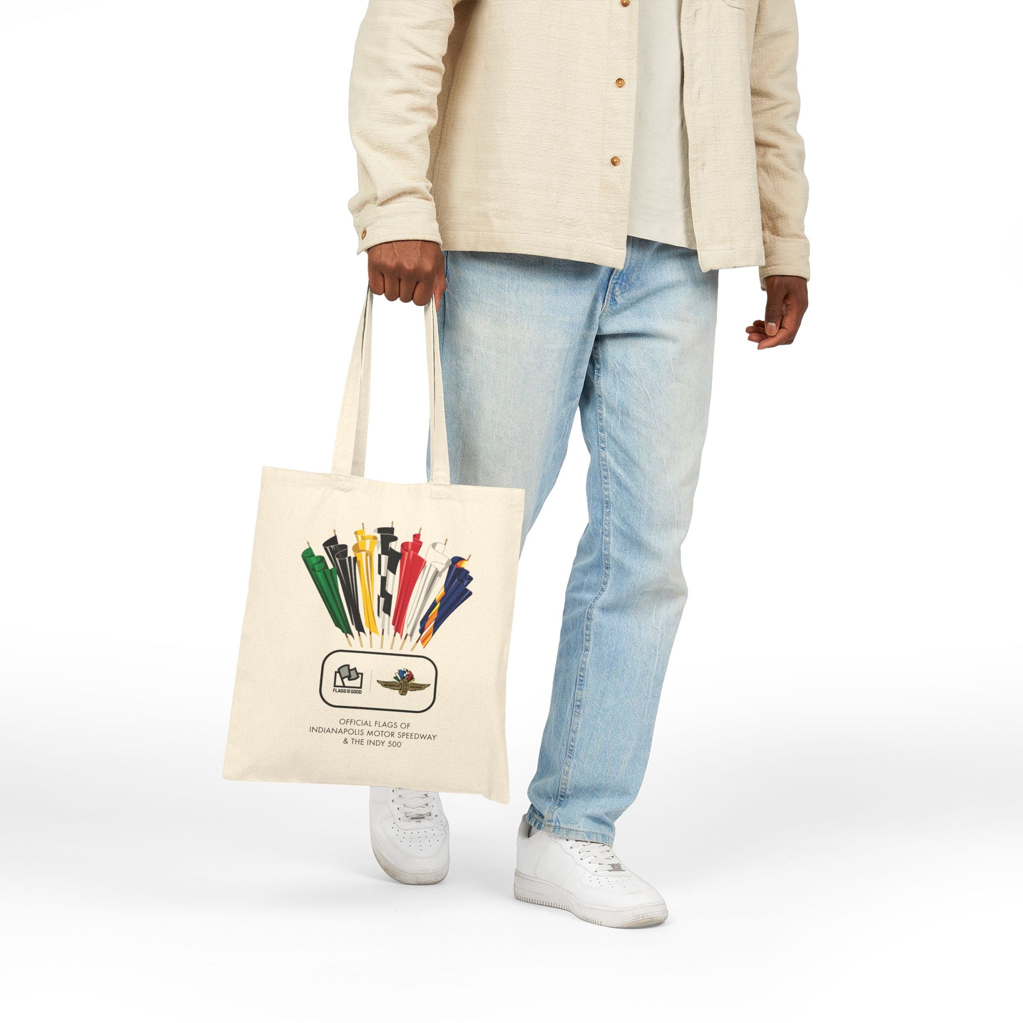 person holding a cream-colored tote with a vintage Indianapolis 500 racing flag design