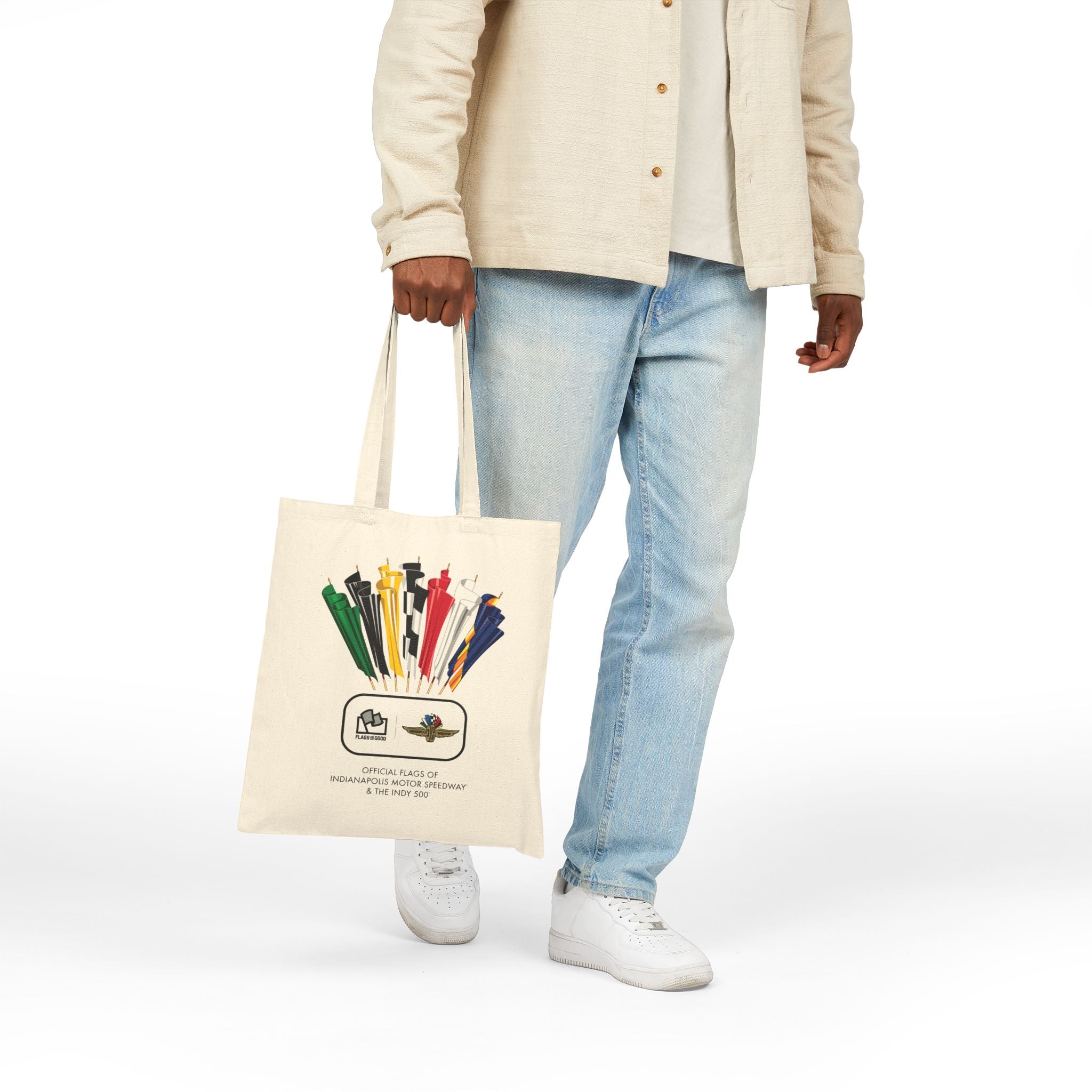 person holding a cream-colored tote with a vintage Indianapolis 500 racing flag design