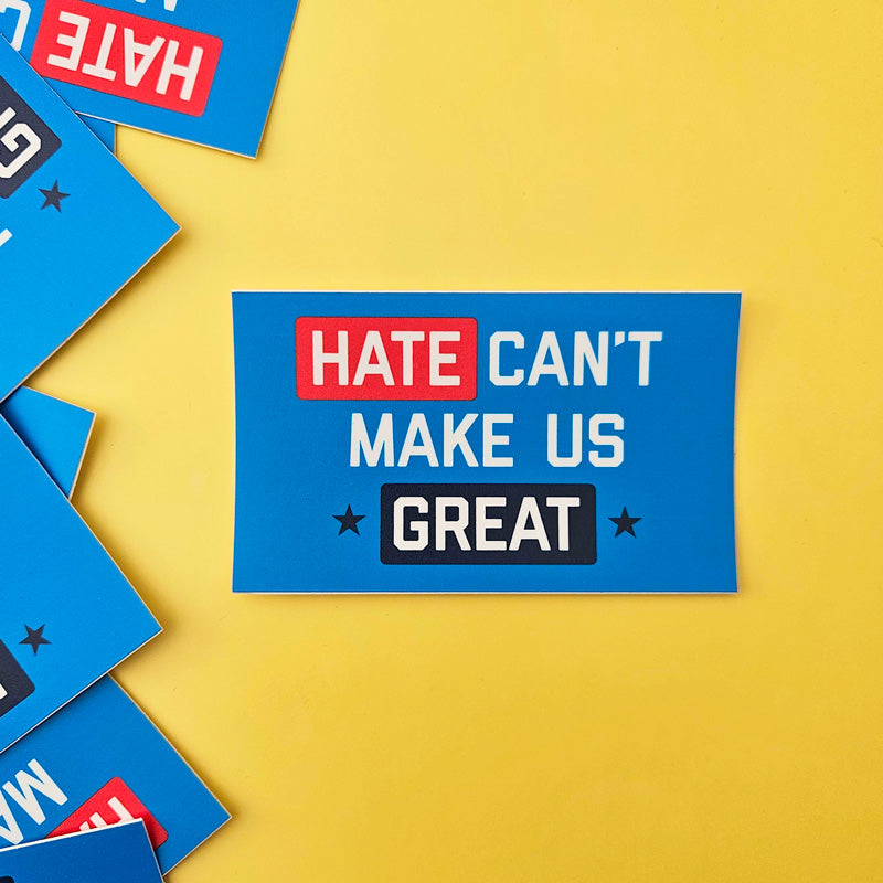 Blue sign with 'Hate Can't Make Us Great' text on a yellow background
