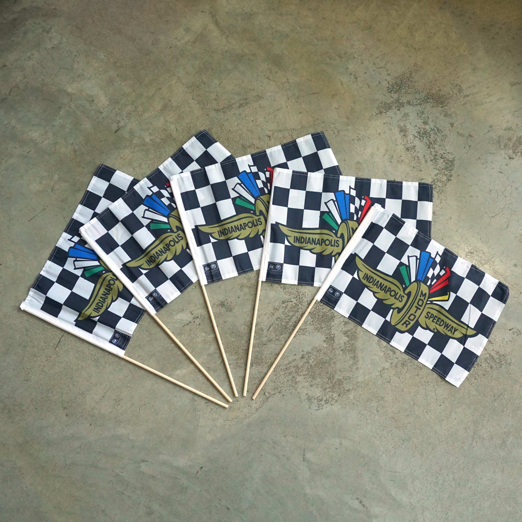 Set of checkered flags with 'Indianapolis Motor Speedway' branding on a concrete surface