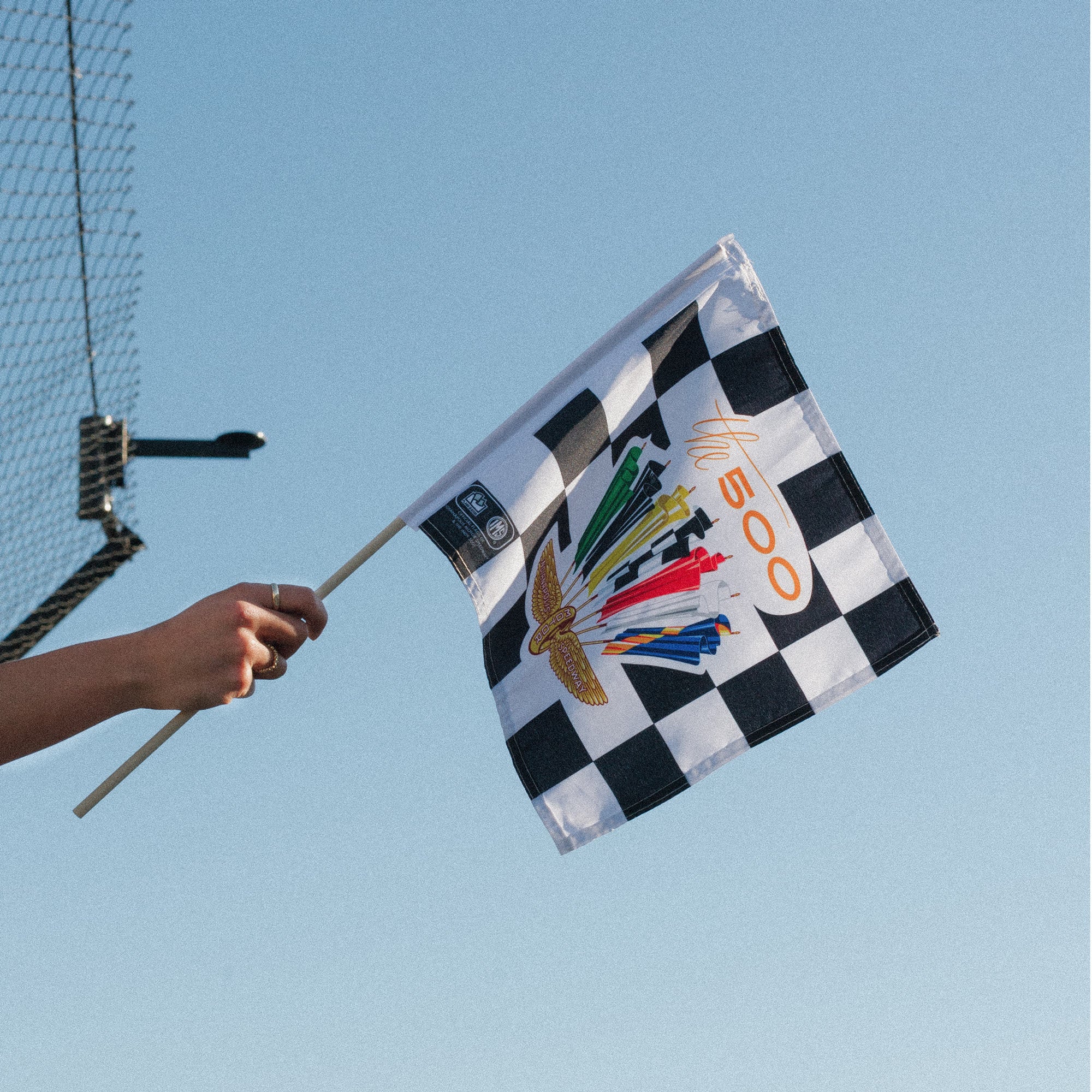 Checkered flag with racing symbols against a clear blue sky