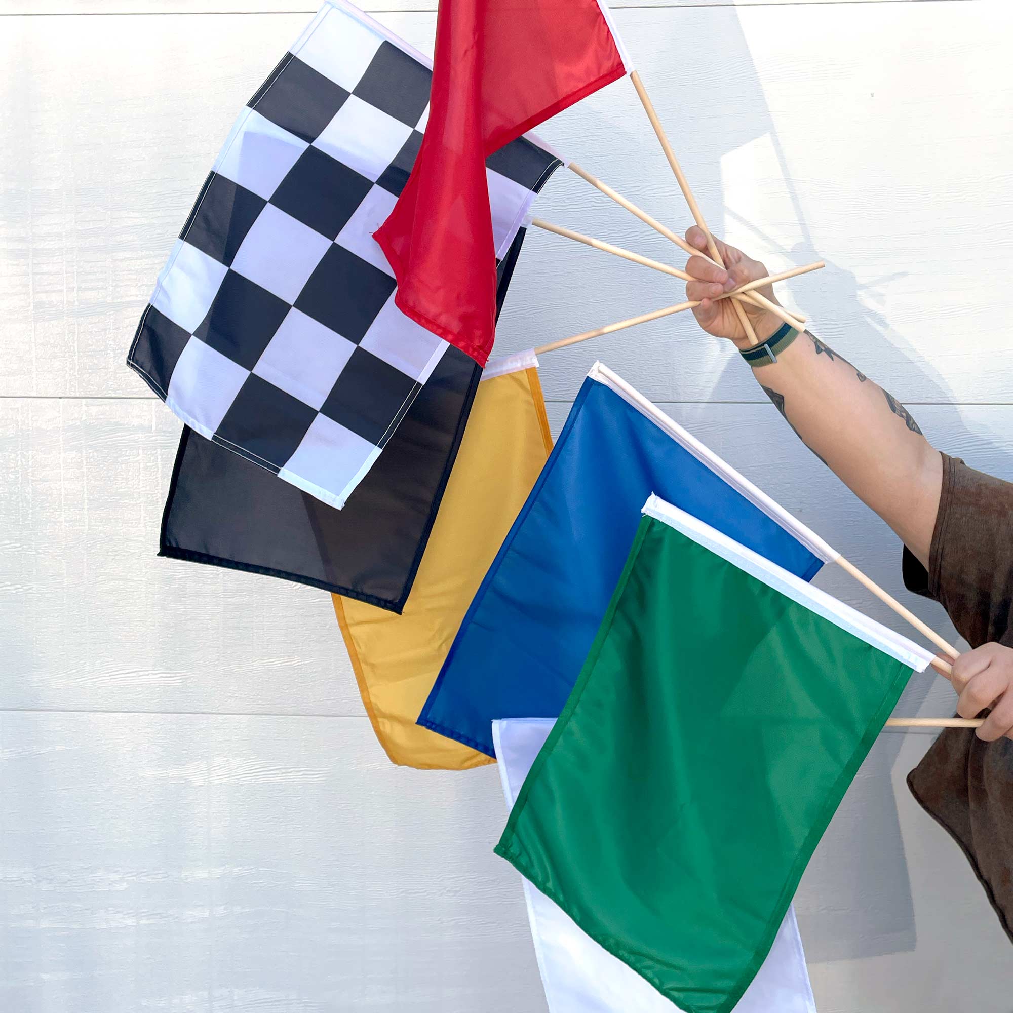 Set of 7 multicolor racing stick flags held by a person against a light background