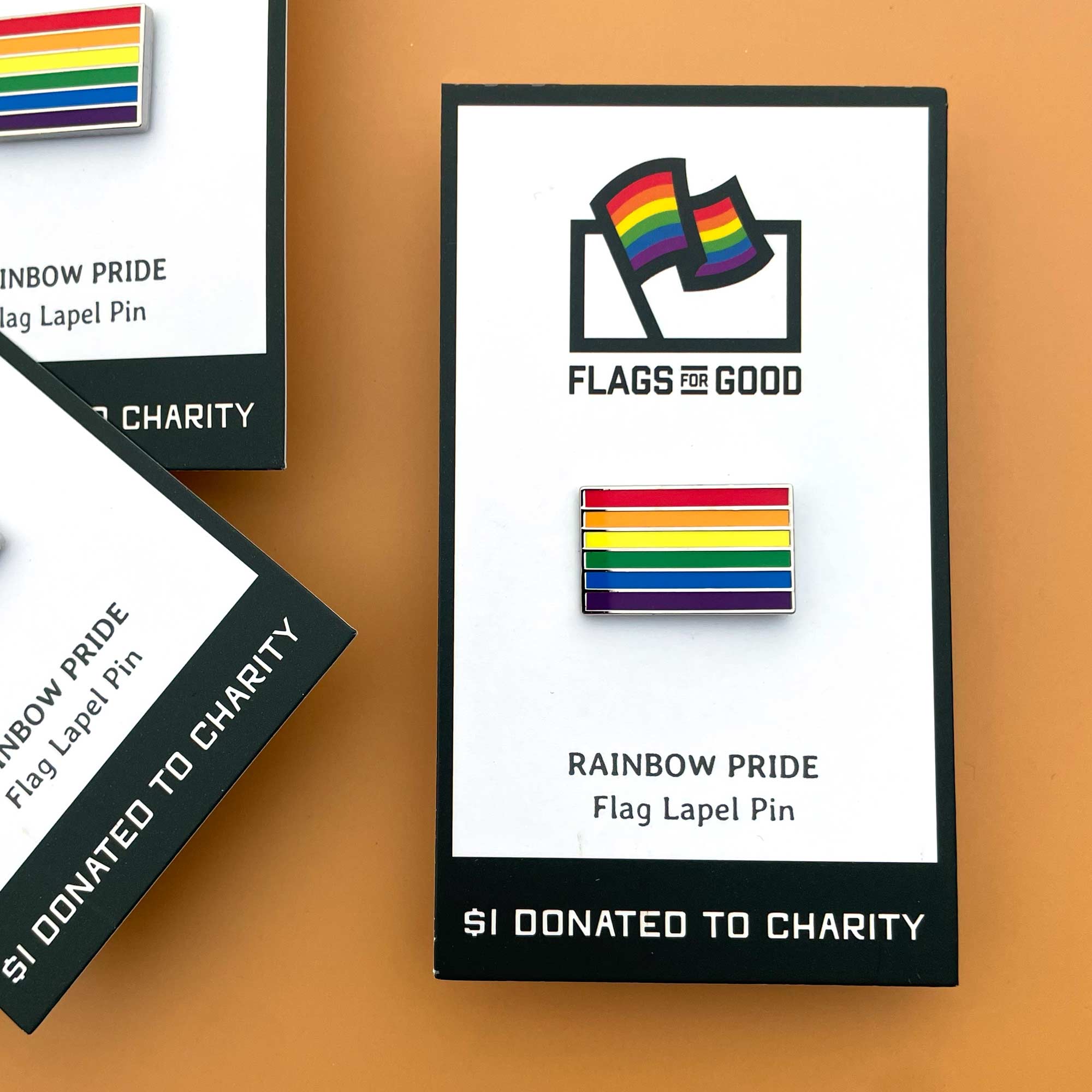 Rainbow pride flag lapel pin with 'Flags for Good' branding on a white card.