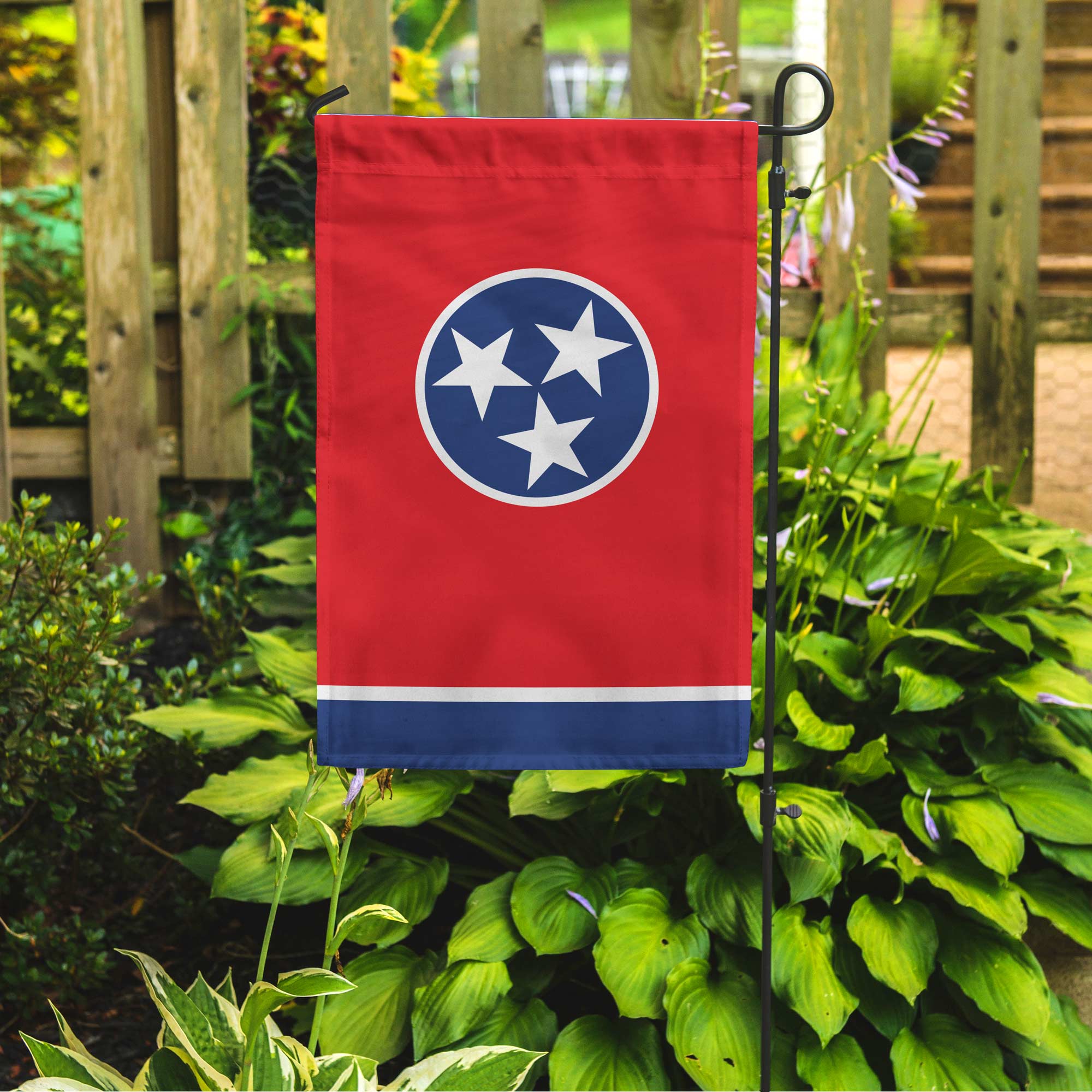 Tennessee flag hanging vertically on a garden pole in a green garden