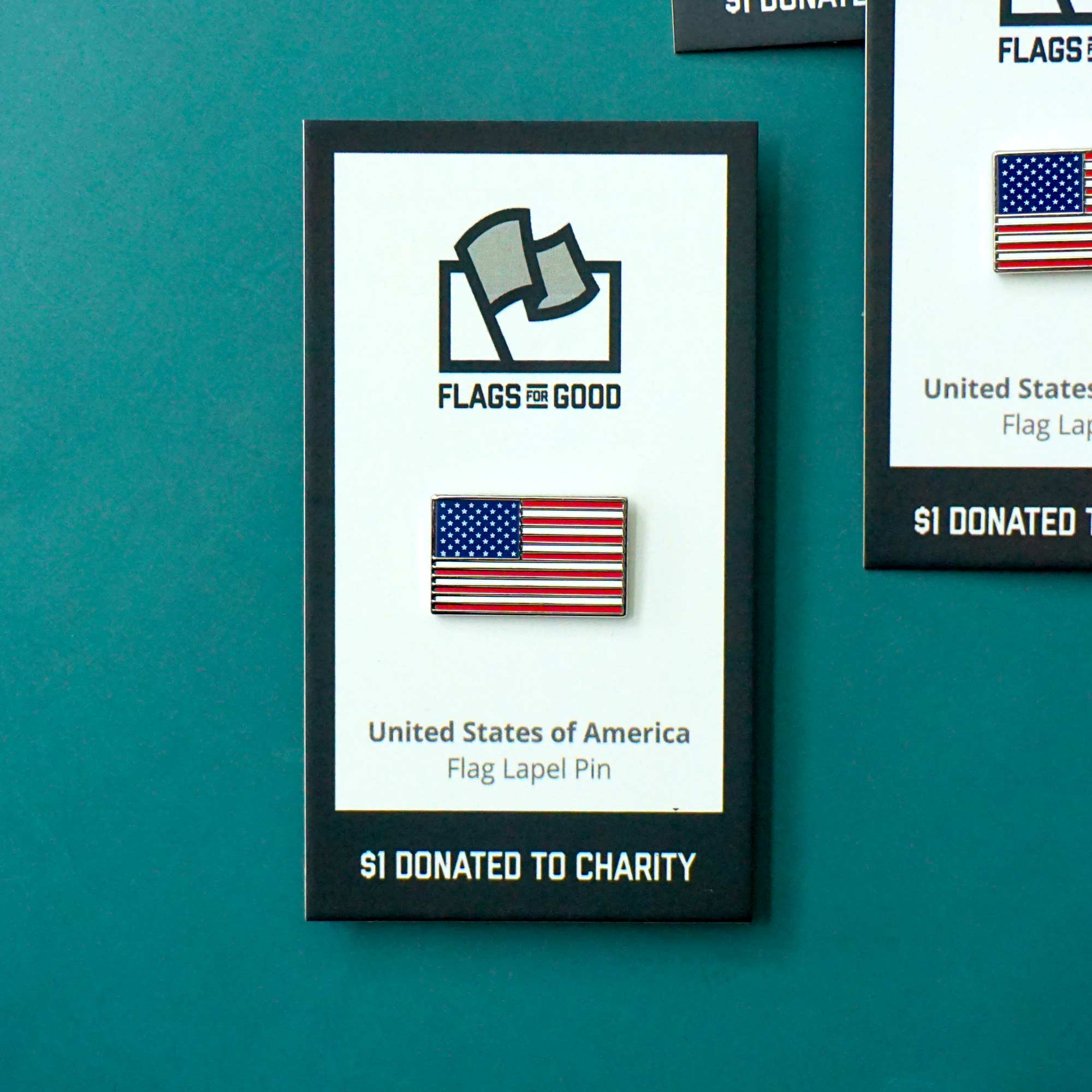United States flag lapel pin displayed on a teal wall with 'Flags for Good' branding.