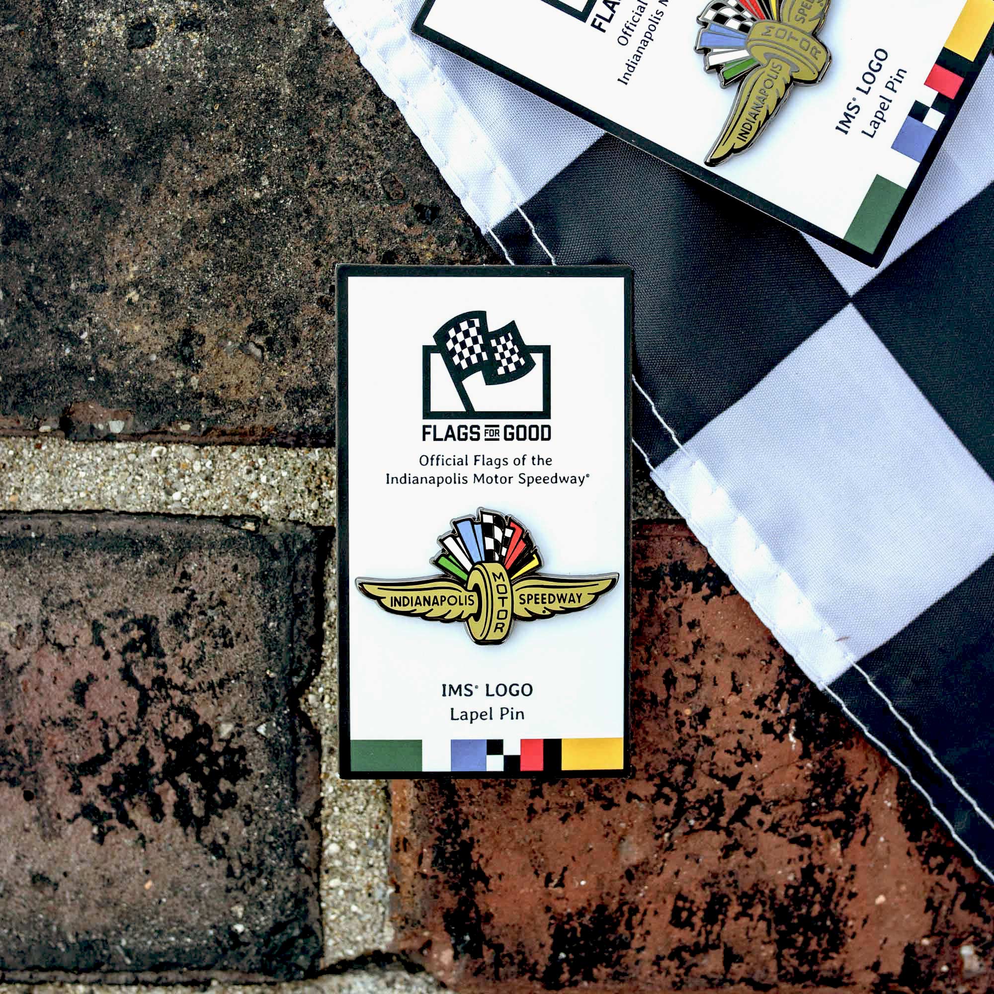 Indianapolis Motor Speedway wing and wheel logo-shaped pin on a white card with "Flags for Good" printed on top of product card