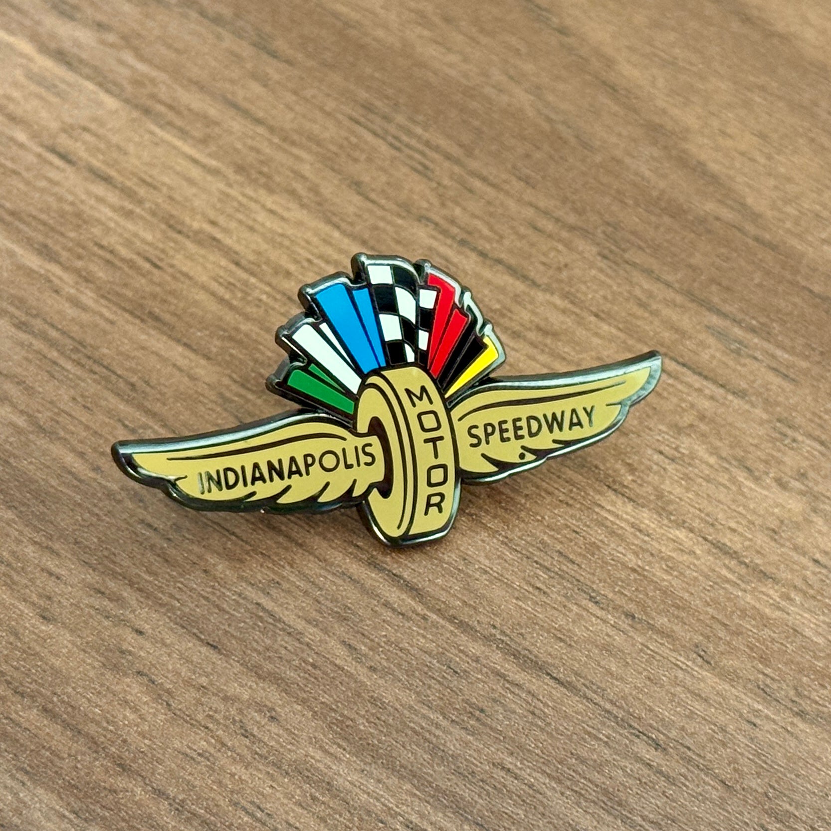 Indianapolis Motor Speedway logo pin on a wooden surface