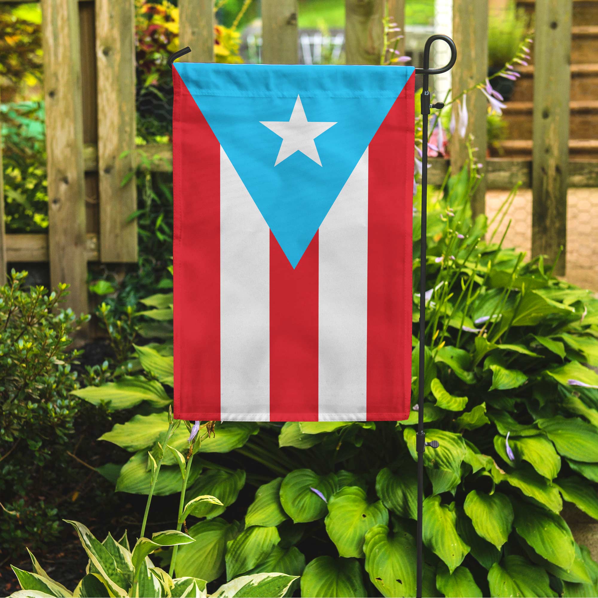 Puerto Rican flag on a garden flagpole with green plants in the background